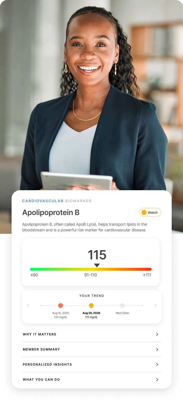 A smiling businesswoman in a blazer, holding a tablet in a bright office.