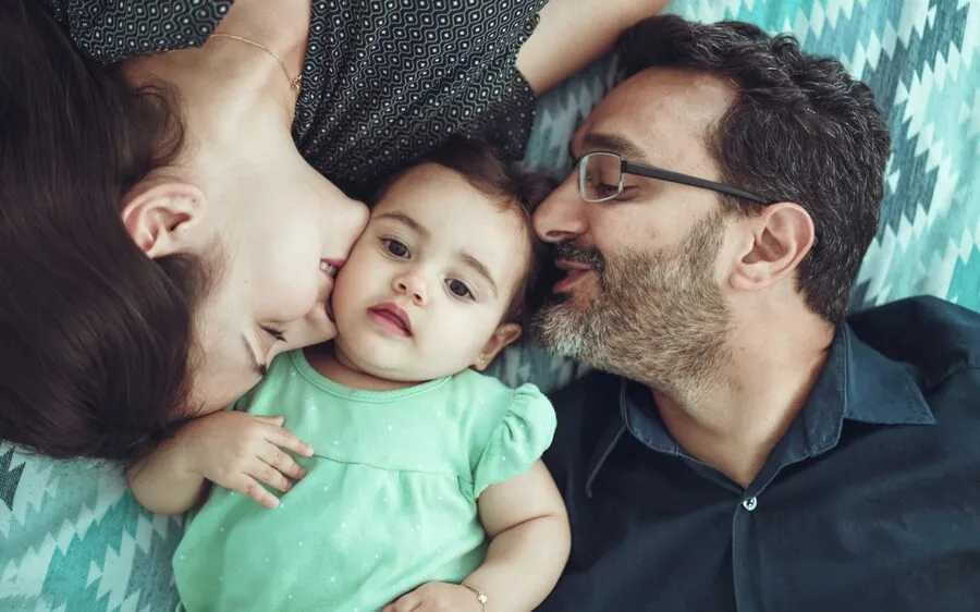 A couple nuzzling their baby between them.