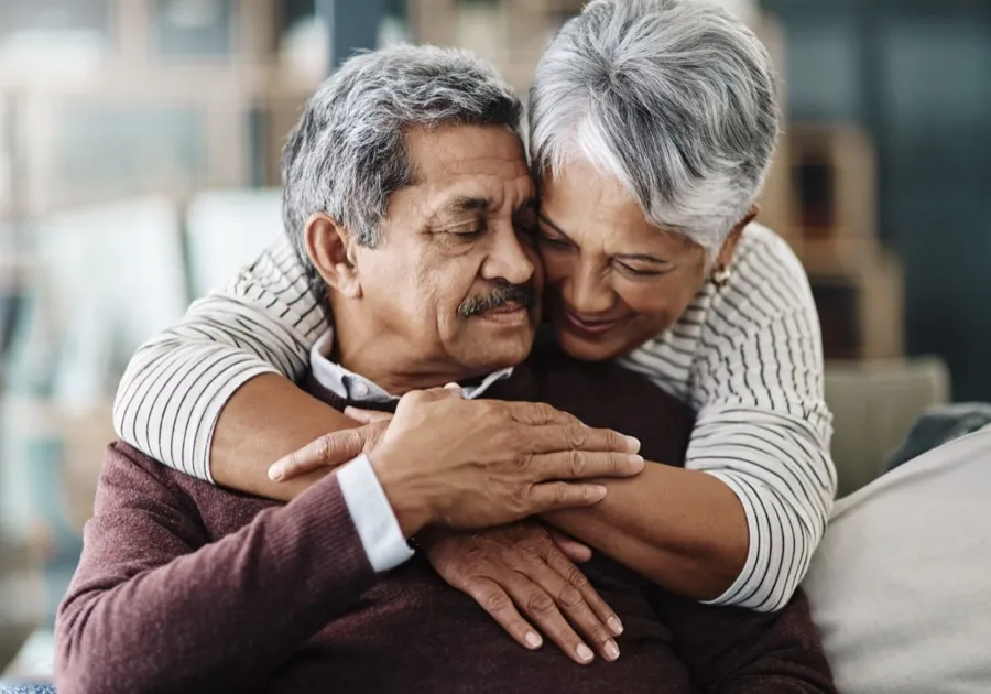 An older couple embracing warmly at home.