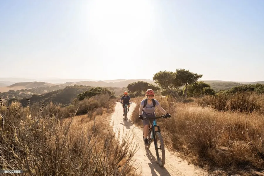 A cyclist riding a gravel path through golden grass.
