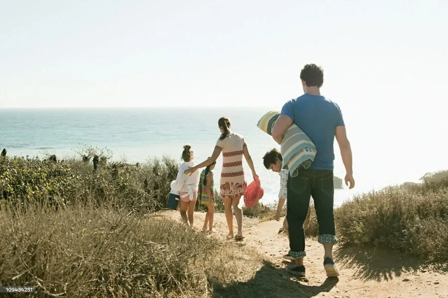 A family walking along a coastal path toward the ocean.