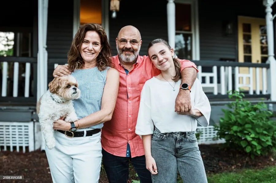 A family of three with their dog on a porch.