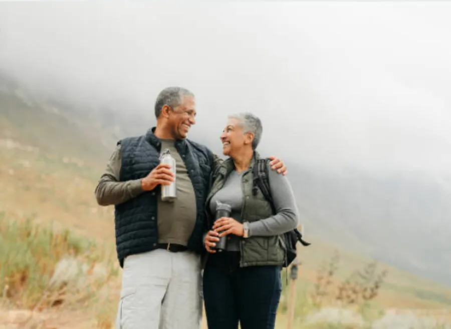 An older couple laughing together on a hiking trail.