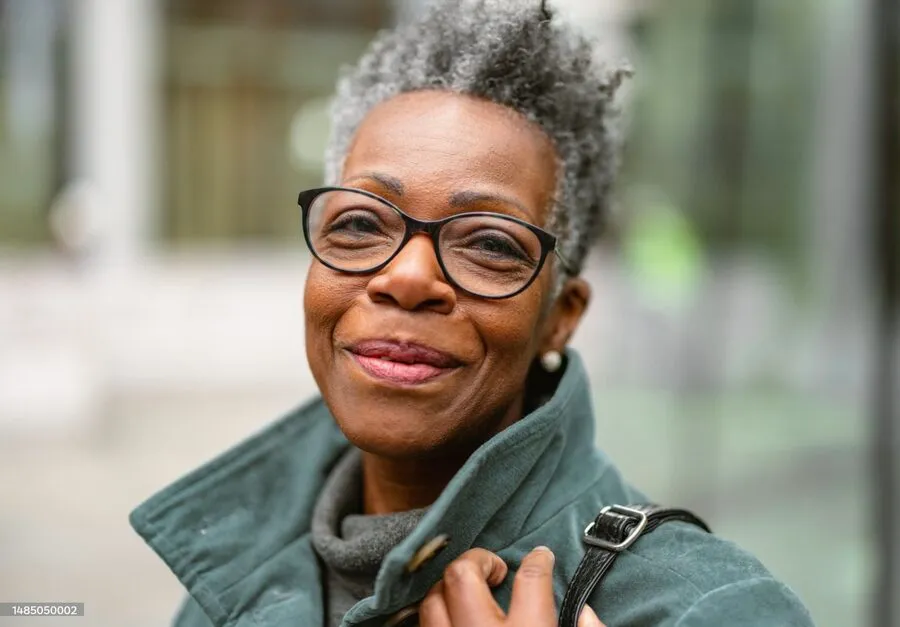An older woman with glasses smiling.