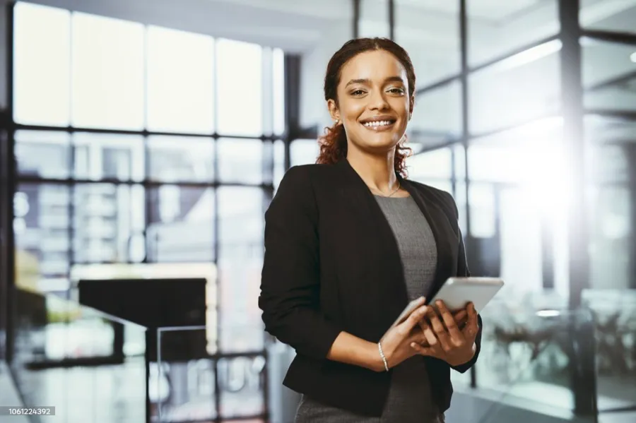 A woman smiling while looking at her phone in an office.